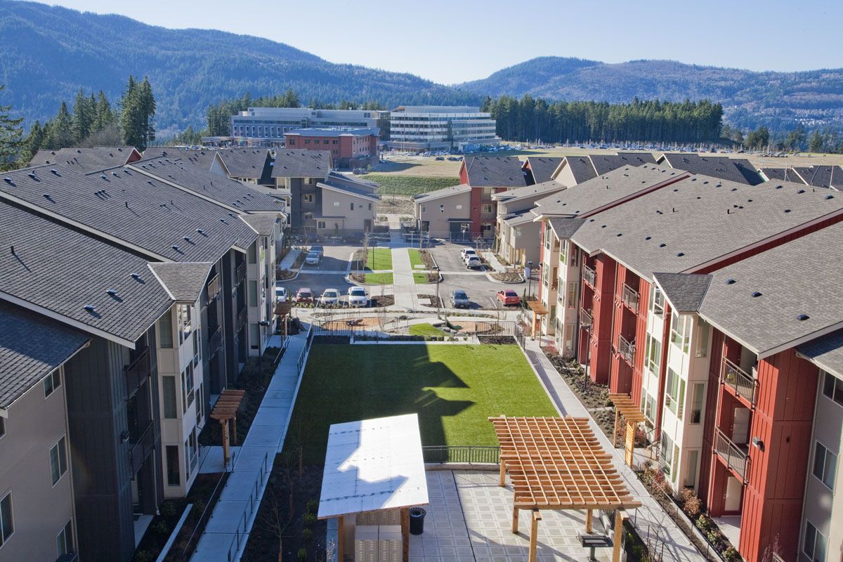 Aerial view of a garden-style apartment community with a central green, mountains behind